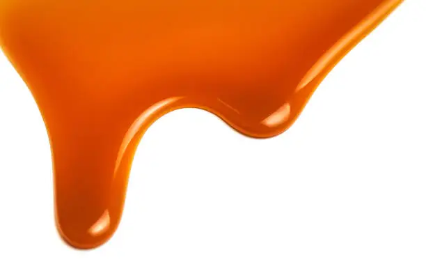 Photo of Sweet caramel sauce isolated on white background close up. Golden Butterscotch toffee caramel liquid 
