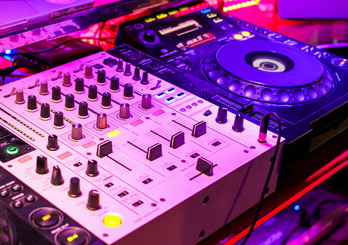 DJ, sound engineer on mixer at live concert plays electronic music or adjusts parameters for musicians, night party event