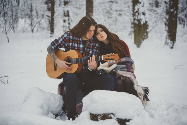 istock Man plays guitar to his girlfriend in winter forest 880973622