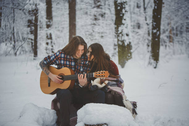 istock Man plays guitar to his girlfriend in winter forest 880973660