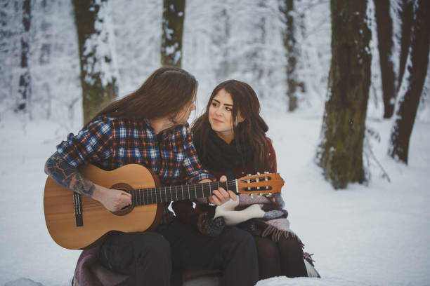istock Man plays guitar to his girlfriend in winter forest 880973730