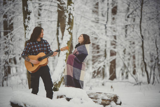 istock Man plays guitar to his girlfriend in winter forest 880975934