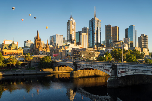 Hot air balloons floating above the Melbourne skyline at dawn.
