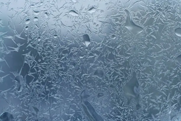 window glass with frost and water drops