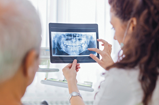 Female dentist examining patient x-ray and talking to a patient