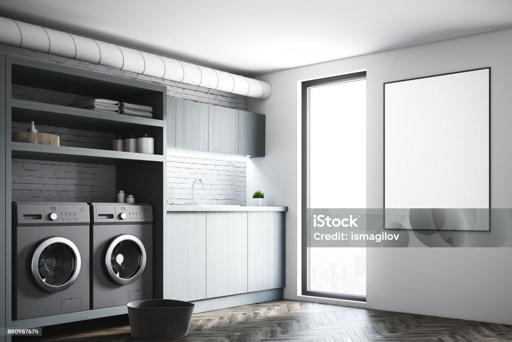 Gray laundry room, gray washing machines, poster Modern laundry room interior with white and brick walls, gray wooden consoles and shelves and two white washing machines. A poster on the wall. 3d rendering mock up Laundry Stock Photo