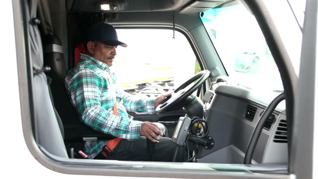 Hispanic man climbing into cab of semi-truck