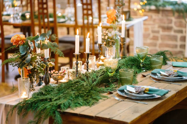 wedding, floral design, treat concept. amazing decor of restaurant table for lovers, on corners of it there are bouquets of nice flowers and at the center of table there are branches of conifer trees - flower arrangement dining room decor dining imagens e fotografias de stock