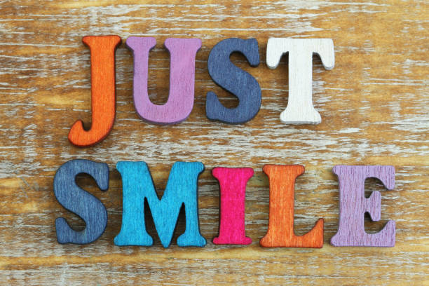 istock Just smile written with colorful letters on rustic wooden surface 880989052