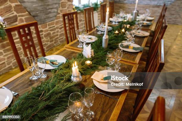 Winter Atmosphere Celebration Concept In The Dining Room There Is An Elegant Furniture Made Of Natural Materials Long Table Served And Decorated With Branches Of Spruce And Candles Stock Photo - Download Image Now