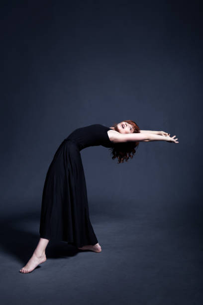 istock Dancer in a black dress is dancing in the dark studio 880993668