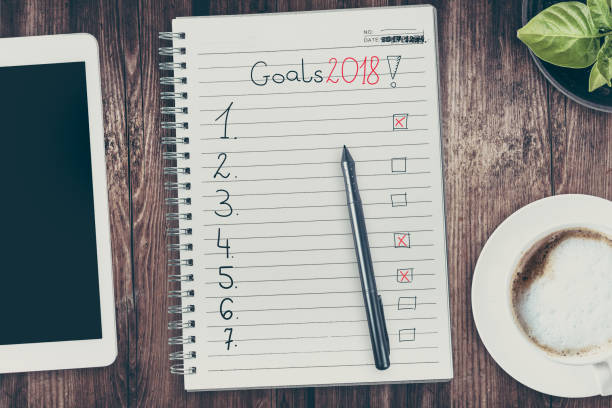 istock Goals in 2018. View from the top of the flat lying objects on the table and in the notebook recorded goals for 2018. Filtered in instagram style. 880993928