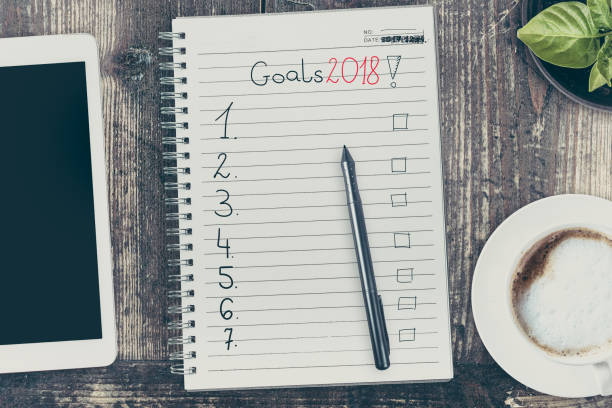 istock Goals in 2018. View from the top of the flat lying objects on the table and in the notebook recorded goals for 2018. Filtered in instagram style. 880993934