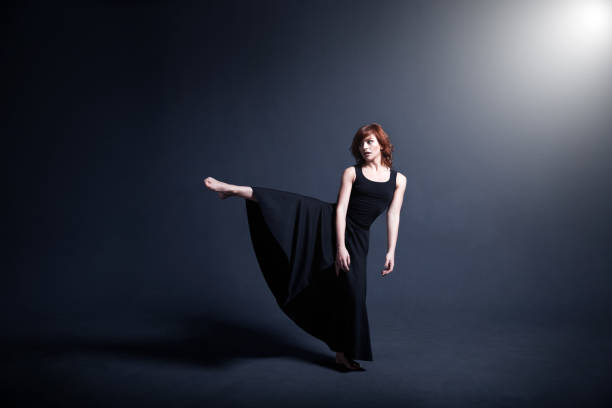 istock Dancer in a black dress is dancing in the dark studio 880994148