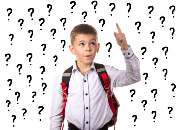 istock Intelligent school boy with idea for answering the hard question, surrounded with question marks 880994254