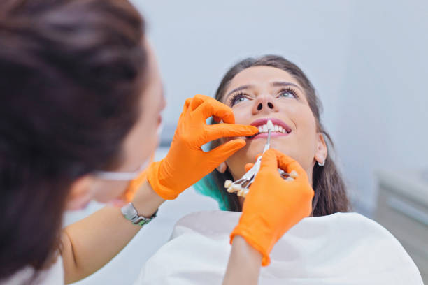 Dentist choose the color of teeth Woman having her teeth examined at dentist office. Female dentist choosing the right color of teeth dental crown stock pictures, royalty-free photos & images