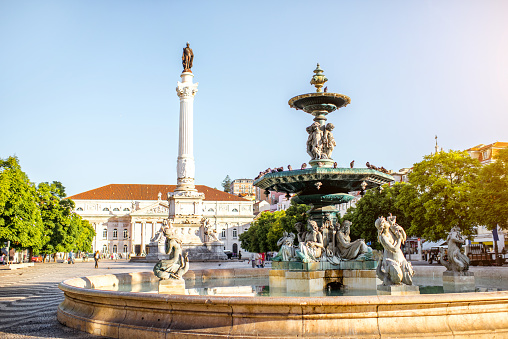 Beautiful view on the fountain on the Rossio square with column during the sunny day in Lisbon city, Portugal