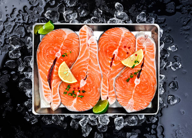 стейки из лосося на льду на черном фоне - freshness seafood crushed ice salmon стоковые фото и изображения