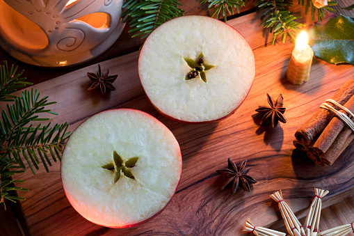 Christmas decoration - halved apple, a candle, cinnamon sticks, star anise, fir branches, and an aroma lamp