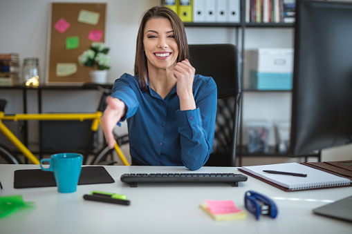 27 years old businesswoman is welcoming a new person in her office