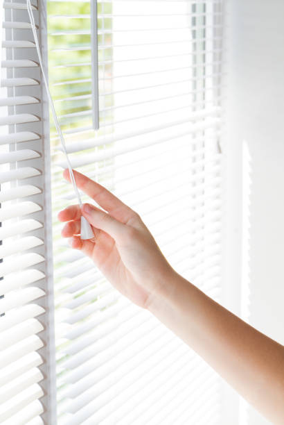 istock Female hand opening white jalousie on window, closeup 881063792