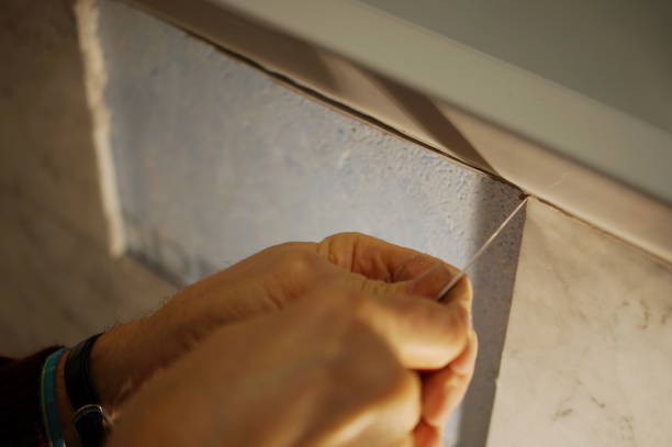 istock Tilers hands are installing a marble tile on a wall in a bathroom. 881064122