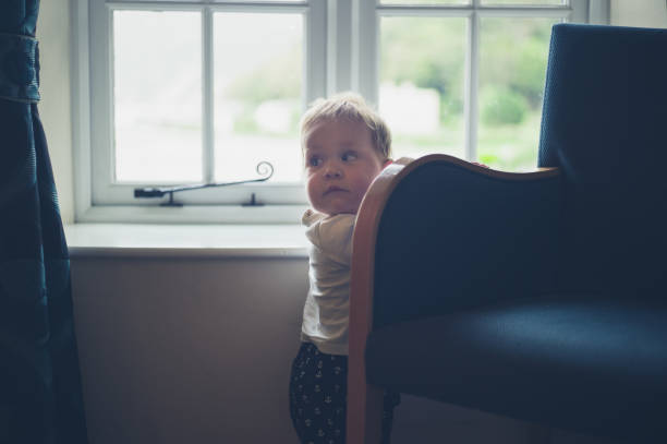 istock Little baby standing by the window 881064220