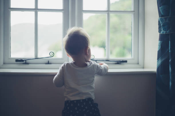 istock Little baby standing by the window 881064272