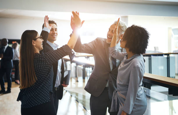 souriant haute fiving d’affaires collègues mutuellement dans un bureau - winning success business businessman photos et images de collection