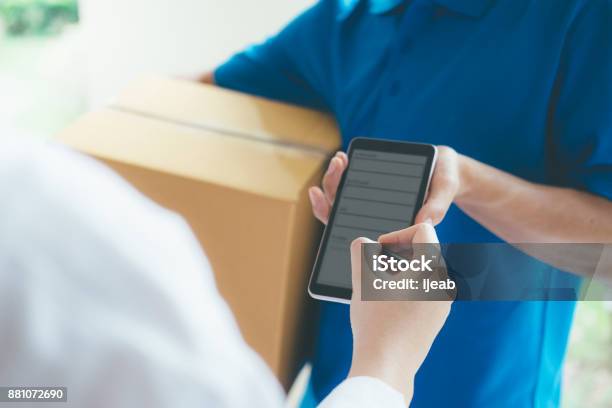 Woman Signing On Digital Device To Delivery Parcel Stock Photo - Download Image Now