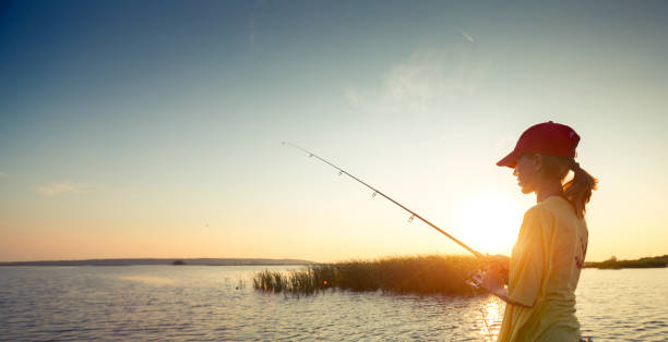Fishing Young lady fishing on the river at sunset broad catch stock pictures, royalty-free photos & images