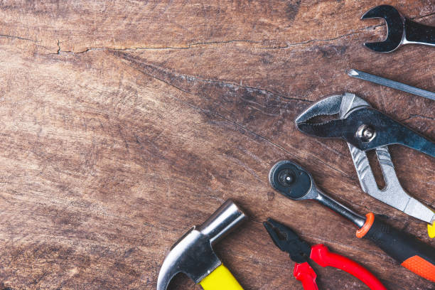 istock Top view of Working tools,wrench,socket wrench,hammer,screwdriver,plier,electric drill,tape measure,machinist square and safety glasses on wooden background.flat lay design. 881073022