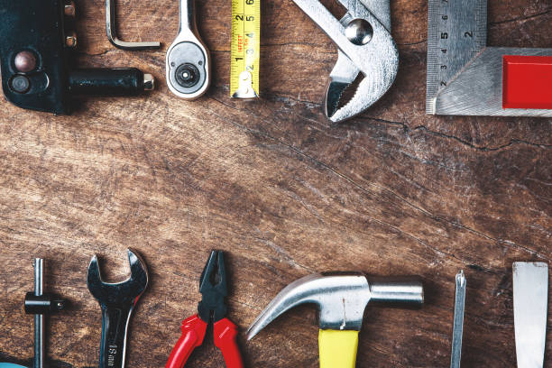 istock Top view of Working tools,wrench,socket wrench,hammer,screwdriver,plier,electric drill,tape measure,machinist square and safety glasses on wooden background.flat lay design. 881073504