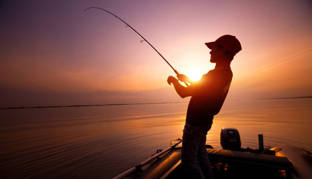 Fisherman Young man fishing on wide river from the boat at sunset broad catch stock pictures, royalty-free photos & images
