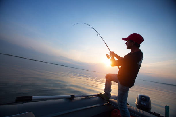 Fisherman Young man fishing from the boat at sunset broad catch stock pictures, royalty-free photos & images