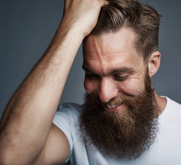 istock Bearded young man with a hand in his hair smiling 881090264