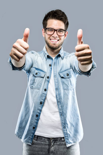 istock Handsome young man expressing happiness with thumb up over gray background. 881095176