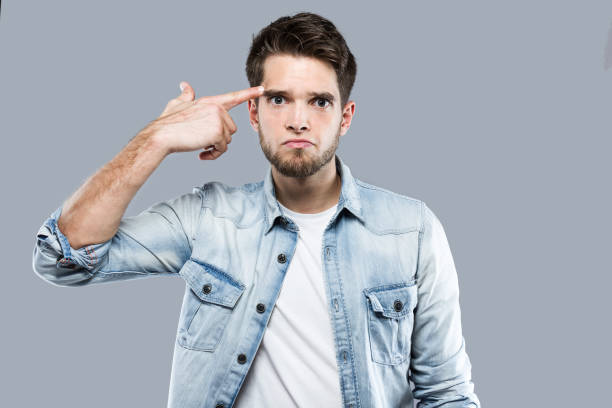 istock Handsome young man making a shooting gesture at her head over gray background. 881095722
