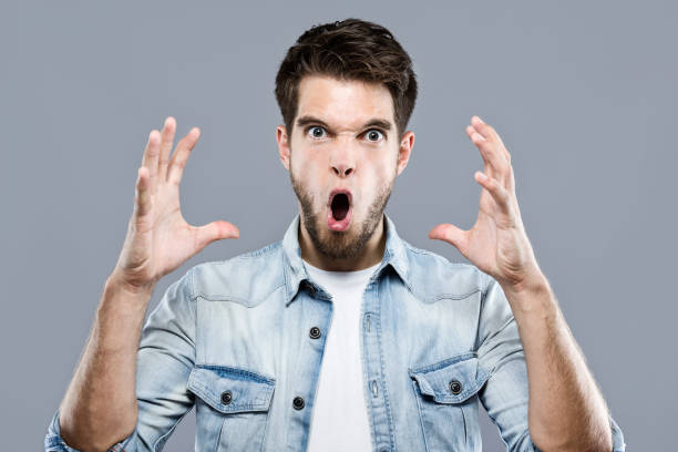 istock Angry young man screaming over gray background. 881095758
