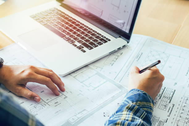 istock Concept architects, equipment architects ,Working On laptop with a blueprint,Model in the office, Vintage, Sunset light.Selective Focus 881108274