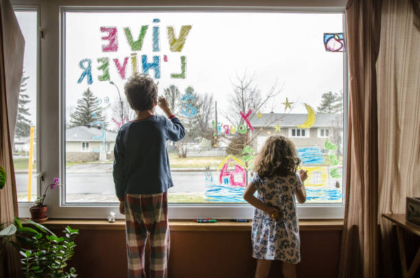 dziewczynka i chłopiec kolorowanki na oknie salonu zimową atmosferę można zobaczyć z zewnątrz - ambiance zdjęcia i obrazy z banku zdjęć