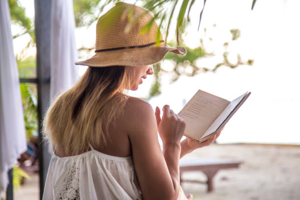 istock girl reading a book on the beach 881128166
