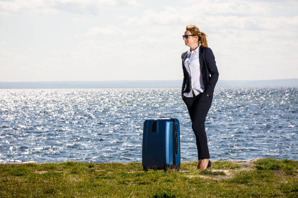 istock Businesswoman standing with suitcase at seaside 881153270