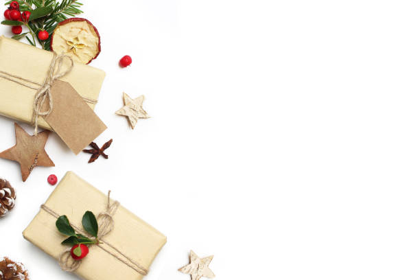 istock Christmas festive styled stock image composition. Handmade gift box, craft paper tag, red berries, wooden stars, dried apple and pine cones isolated on white wooden background. Flat lay, top view 881175736