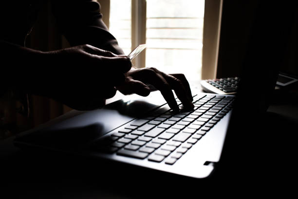 istock Black hands of anonymous hackers holding credit card and using, typing code on keyboard of laptop for remotely reach, receiving personal information online, Networking Crime Payment Security Concept 881210068
