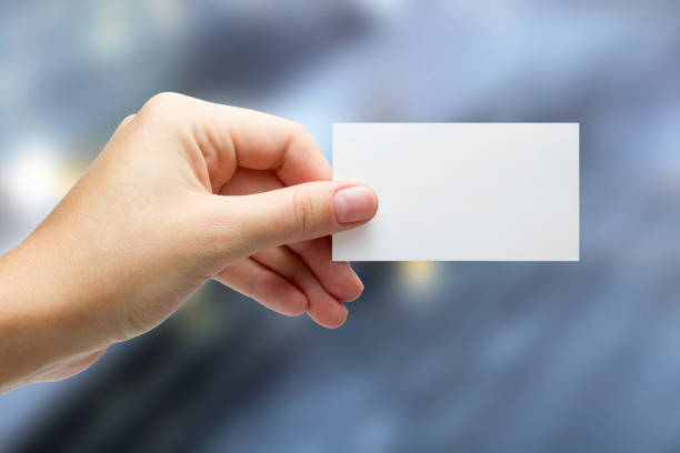istock Hands holding a white business visit id card, gift, ticket, pass, present showing close up on blurred blue background. Copy space for ad text 881229064