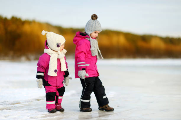 Two little sisters having fun on snowy winter day