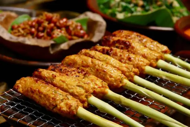 Sate Lilit, the popular Balinese minced seafood satay. Mixture of minced fish, shrimps, coconut with spices and herbs wrapped around aromatic lemongrass skewers. The satays are then grilled on a traditional earthenware grill heated with charcoal flame.