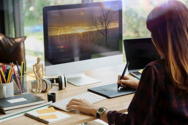 istock Young hipster graphic designer woman using digital graphic tablet while working at modern office, professional female retoucher sitting at modern workspace with wooden table 881308858