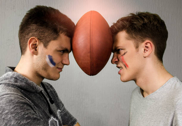 Competitive brothers holding american football ball between their heads